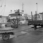 846687 Afbeelding van het overladen van balen papier met behulp van een heftruck op de kade langs de Zaan bij ...